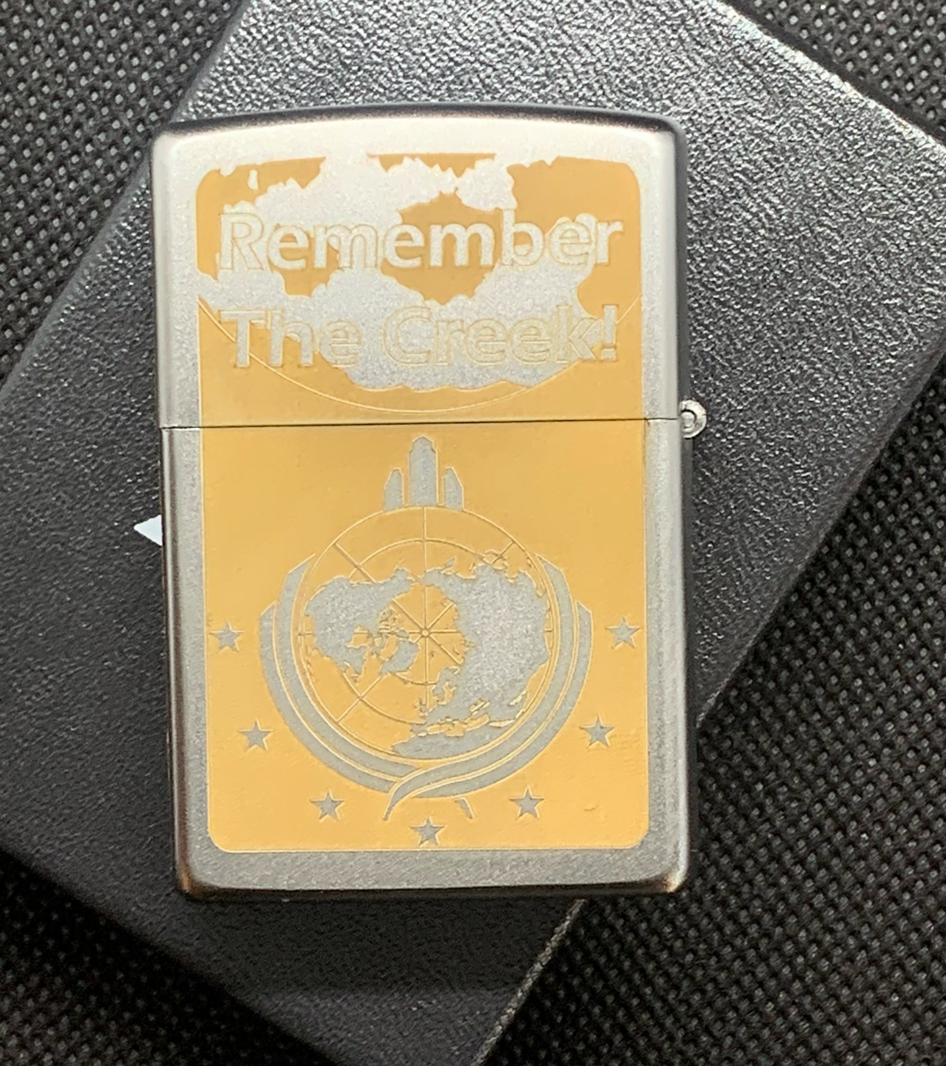 Back of the lighter with the words 'Remember the Creek' above the Super Earth logo